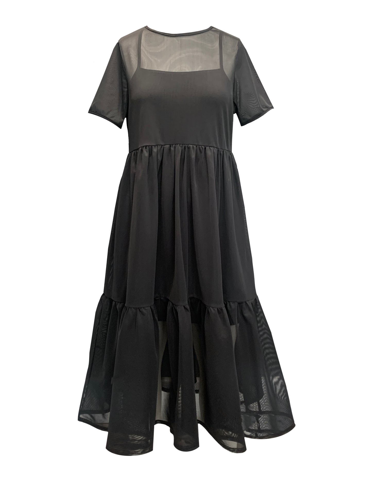 This is a black mesh dress over our nectar cami dress silhouetted against a white background. It has short sleeves and crew neck. There are waist gathers leading to a full skirt which has a deep gathered frill. This is a sheer dress, midi length.