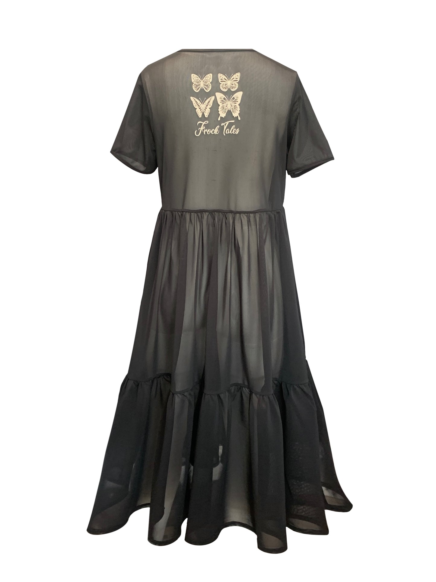 This is the back of a black mesh dress silhouetted against a white background. It has short sleeves and crew neck. There are waist gathers leading to a full skirt which has a deep gathered frill. This is a sheer dress, midi length. Tere is a cream print of four butterflies and the words Frock Tales on the top of the back panel.