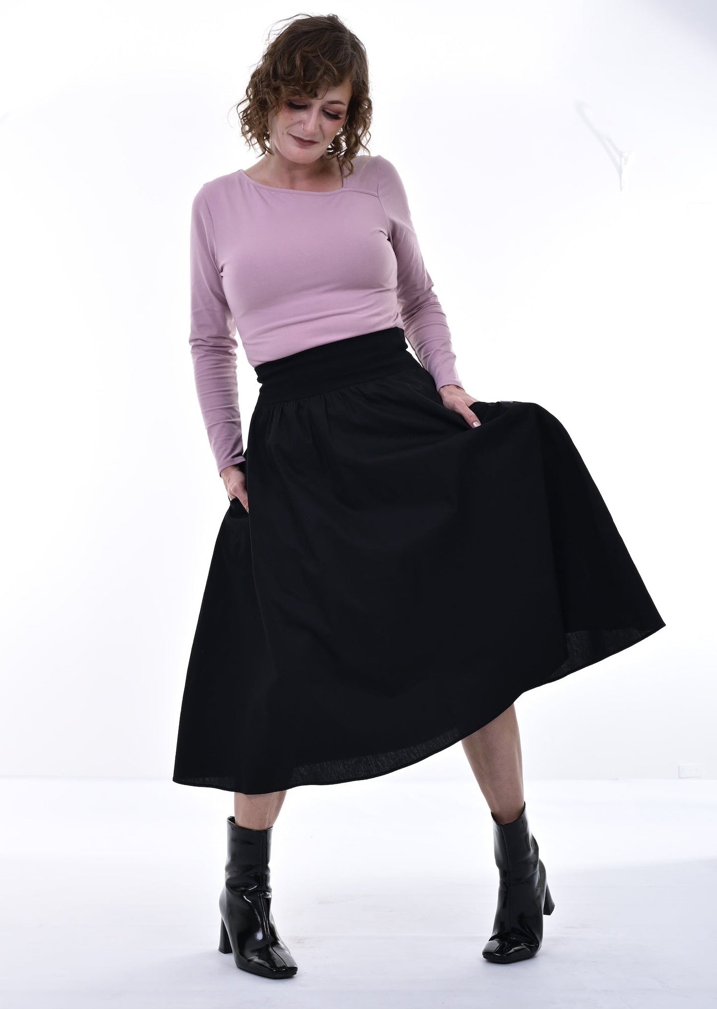 Woman wearing a pink sweater and black skirt on a white background