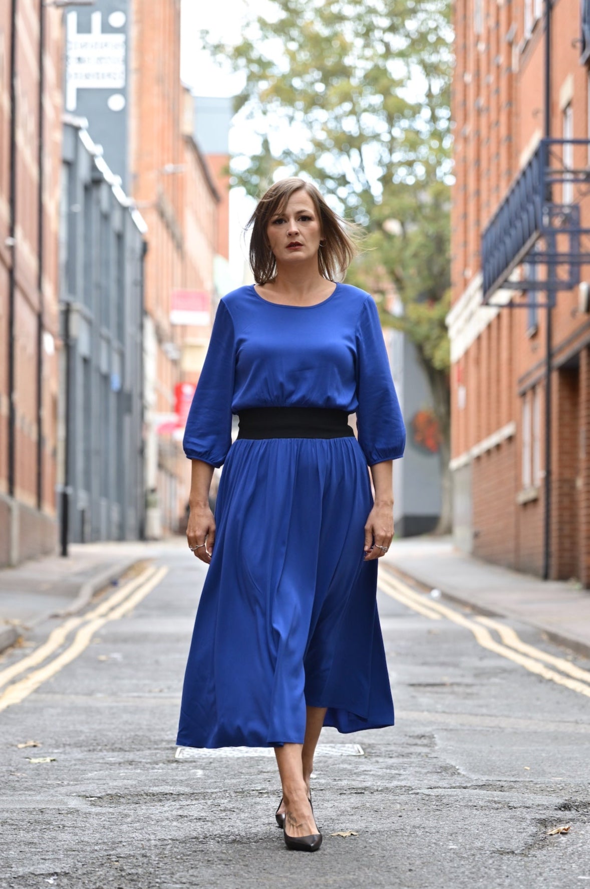 Woman in a blue dress walking down a street.