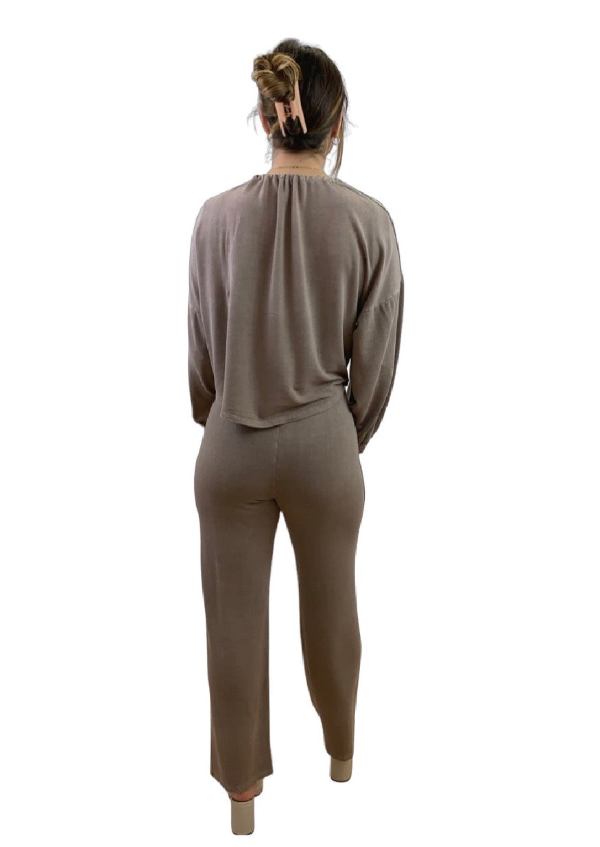This is a back view of a young lady with dark hair pinned. She is silhouetted against a white background. She is wearing a mocha cardigan and mocha trousers.