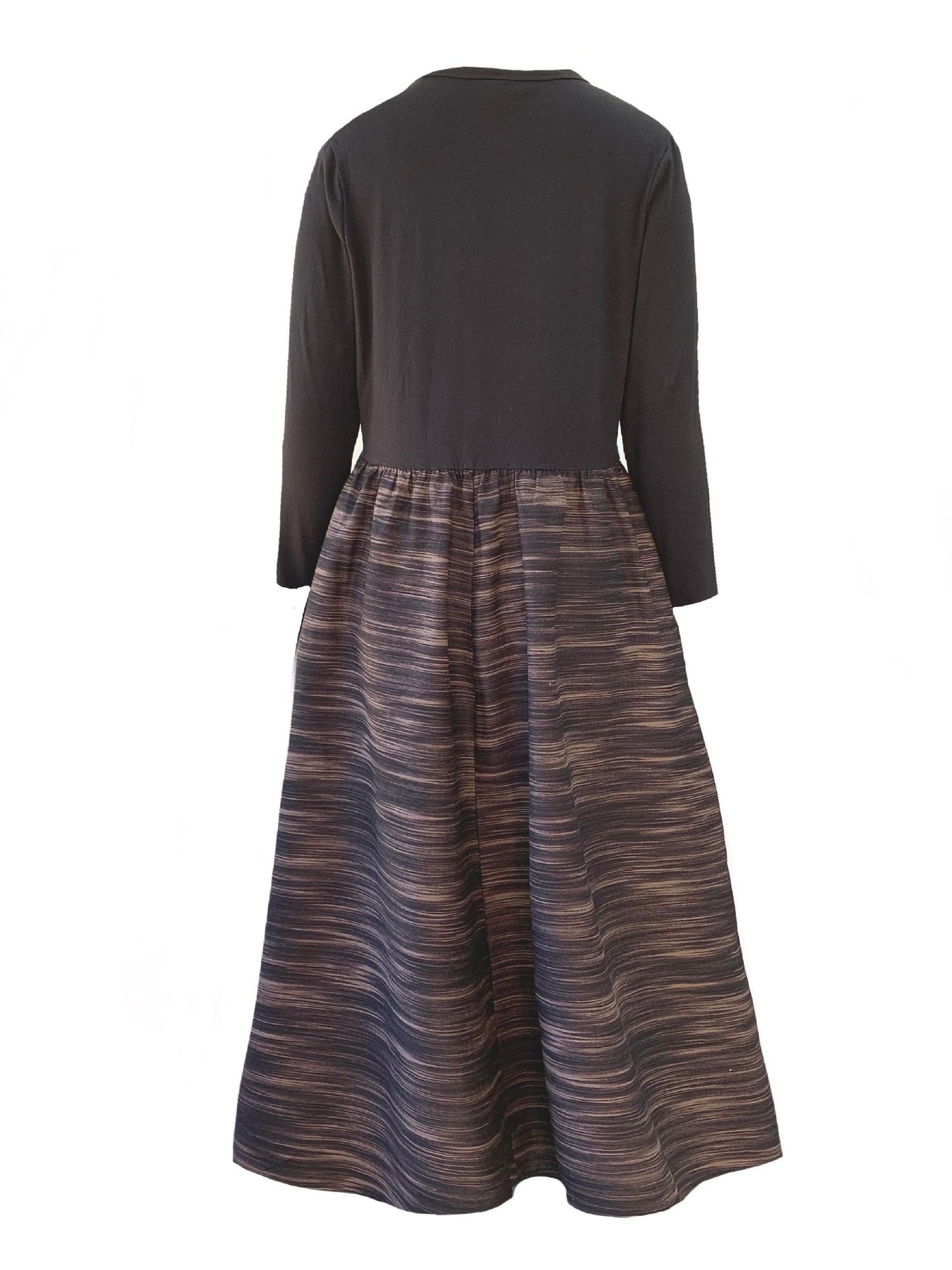 This is a midaxi style dress in dark silhouetted against a white background facing the back. The neckline is round and the sleeves are long. The top gathers in to the waist elastic and the skirt is full with side pockets. The dress is a midaxi length.