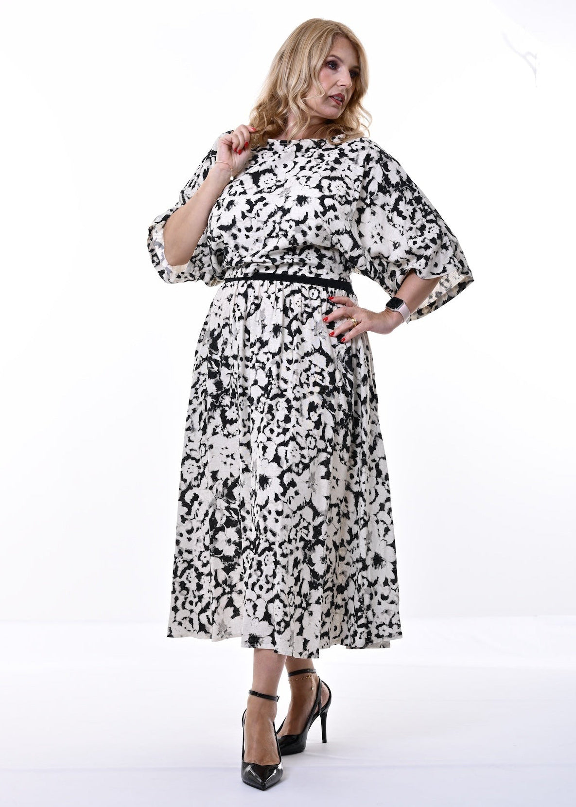A woman modelling a black and beige abstract patterned co-ord with elbow-length sleeves and black waistband, standing against a plain white studio background.