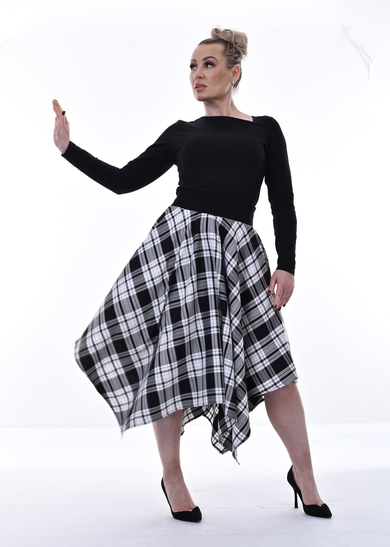 Woman wearing a black top and plaid skirt on a white background