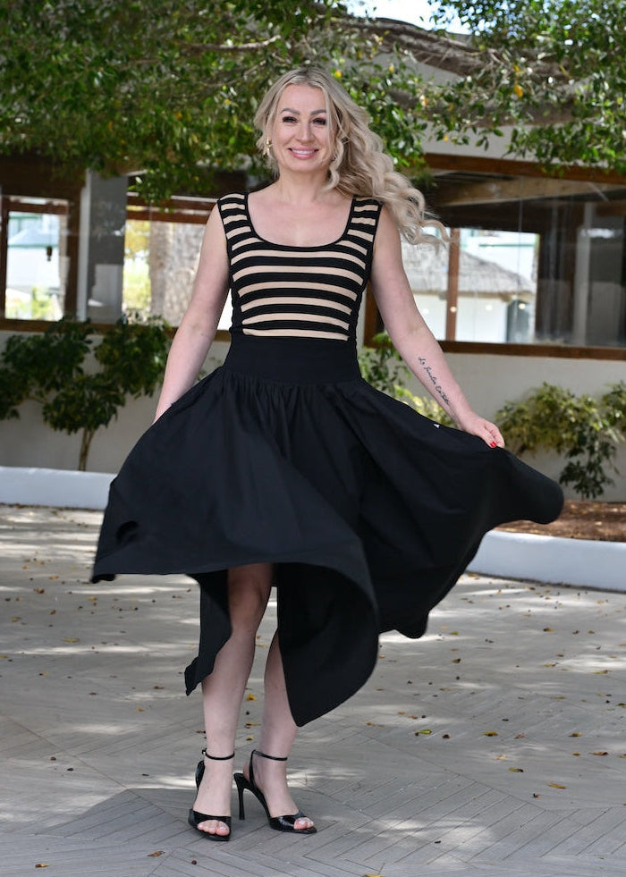 Woman in a black and white striped top and black skirt standing outdoors on a patio.