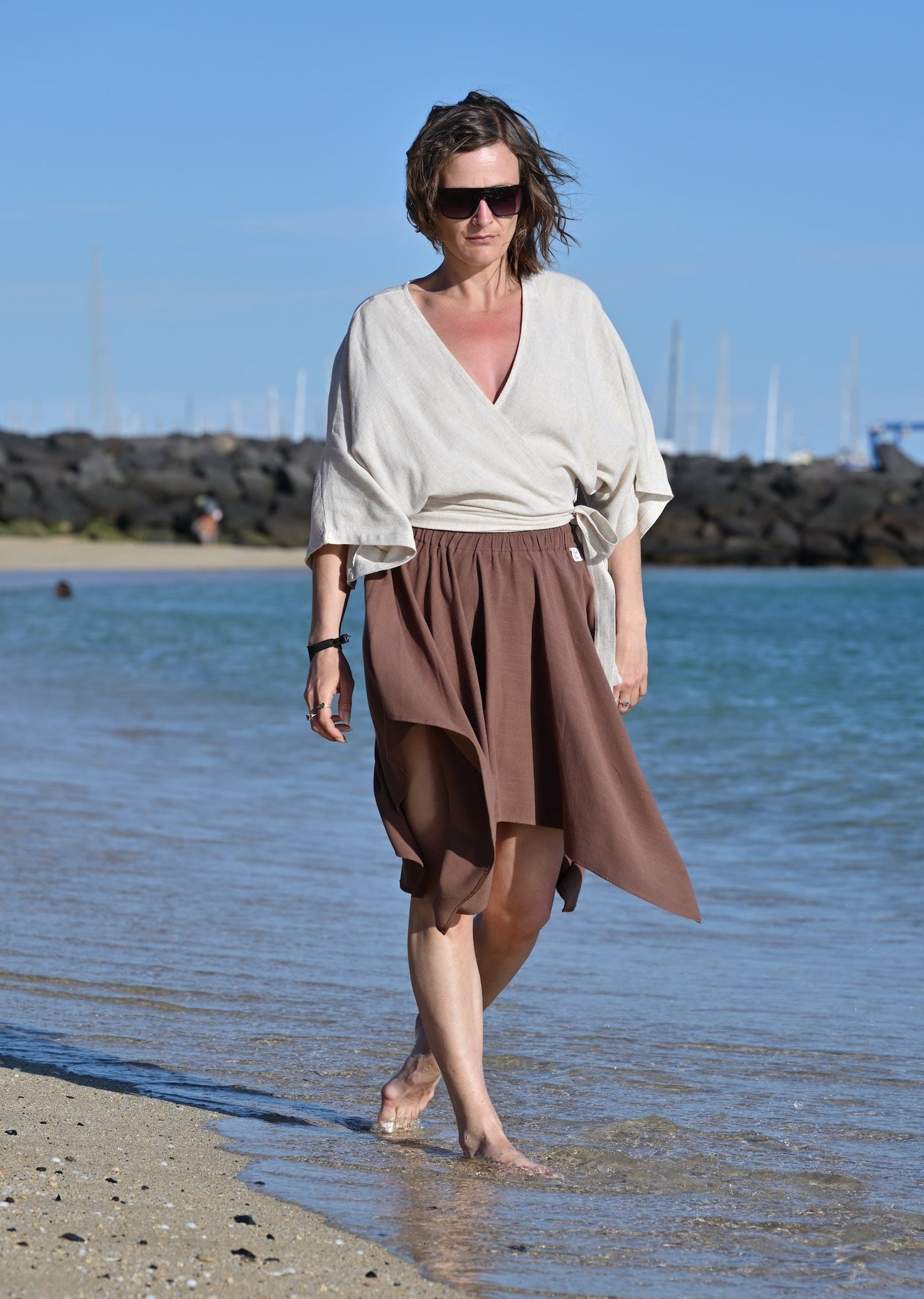 Woman walking on a beach with a clear blue sky and ocean in the background