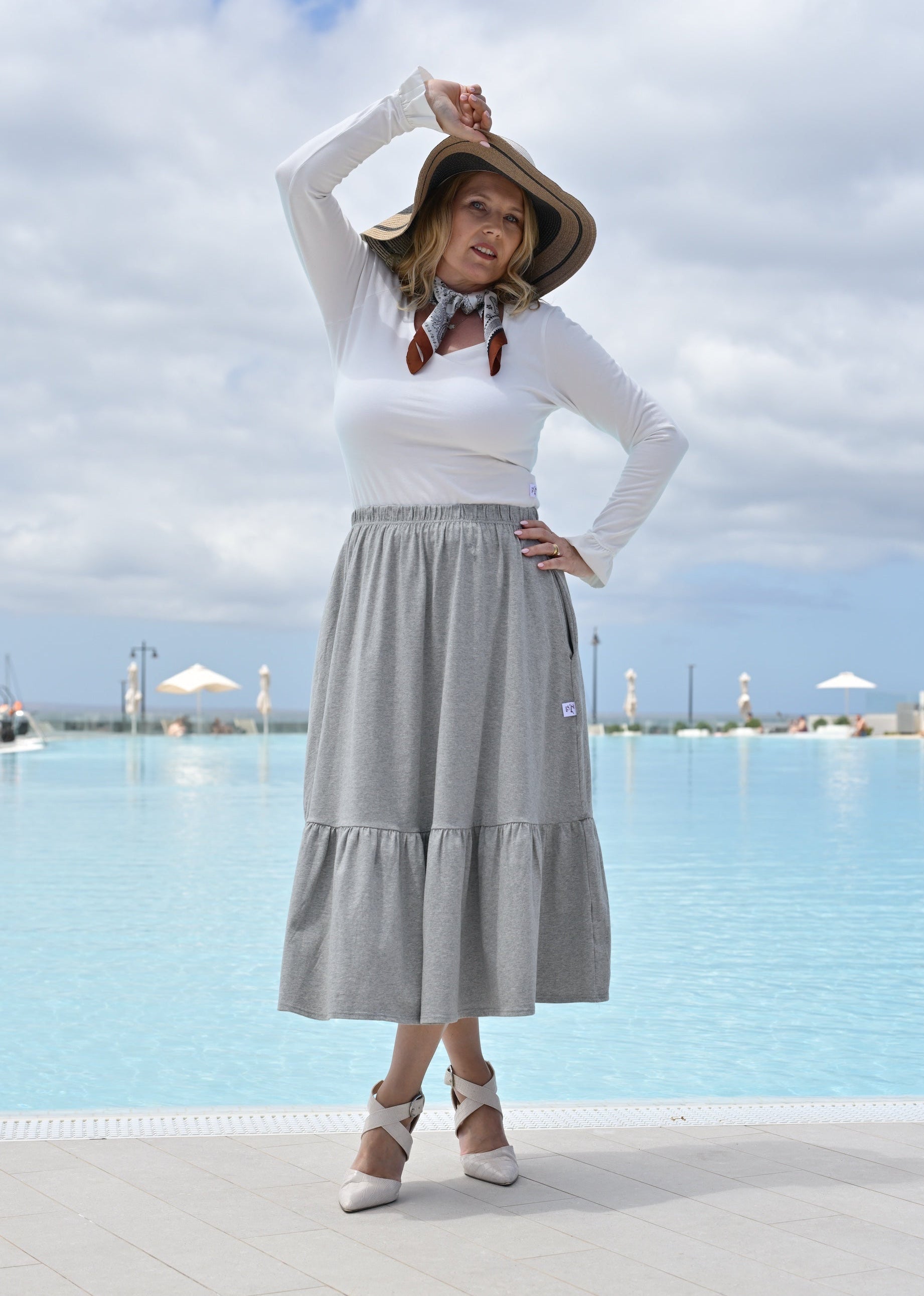 Woman posing by a pool with a scenic background