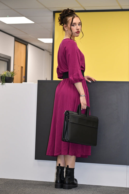 Woman in a magenta dress holding a black briefcase in an office setting