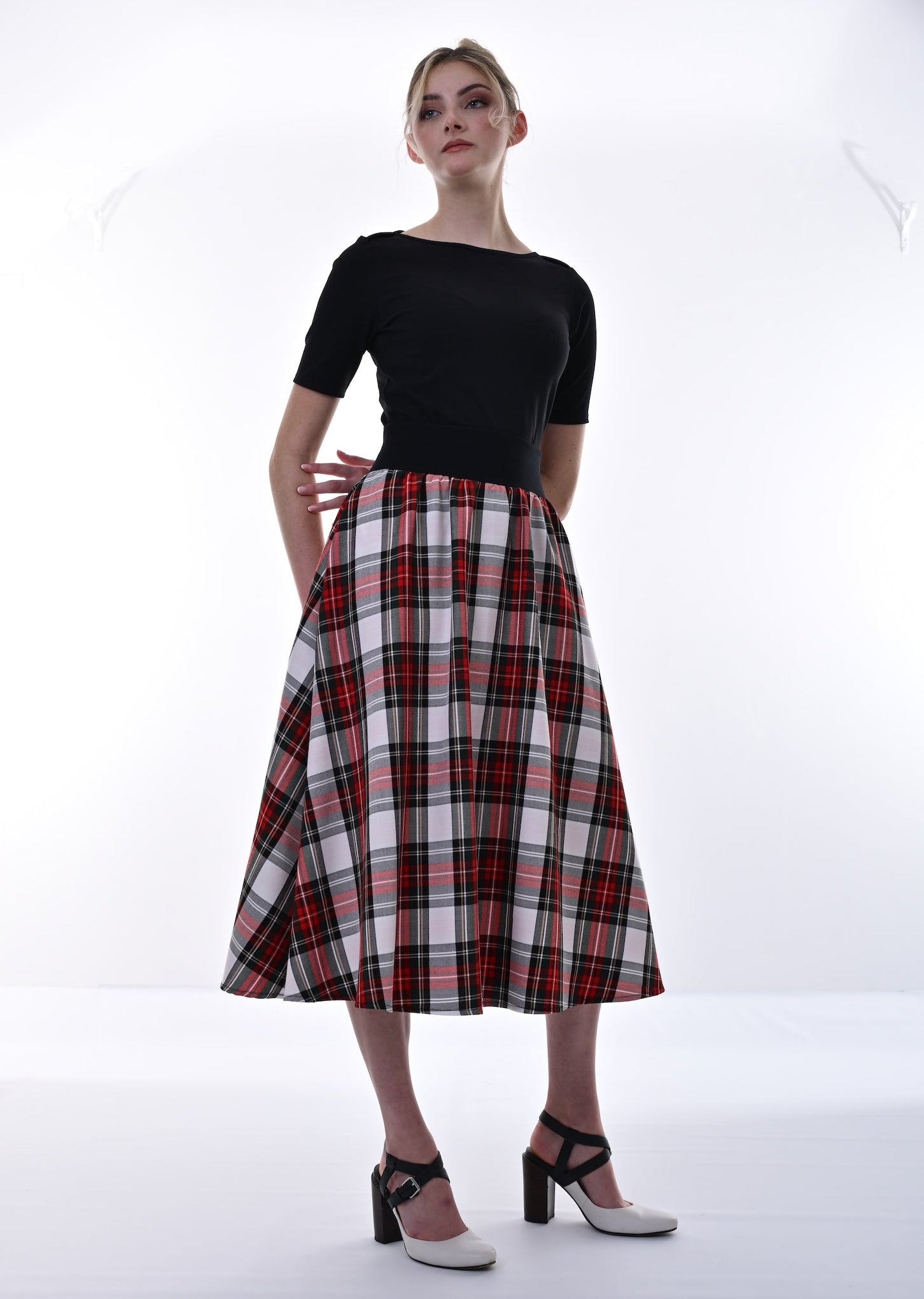 Woman wearing a black top and red plaid skirt on a white background