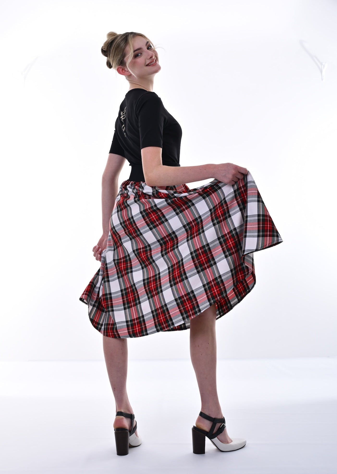 Woman wearing a black top and red plaid skirt on a white background