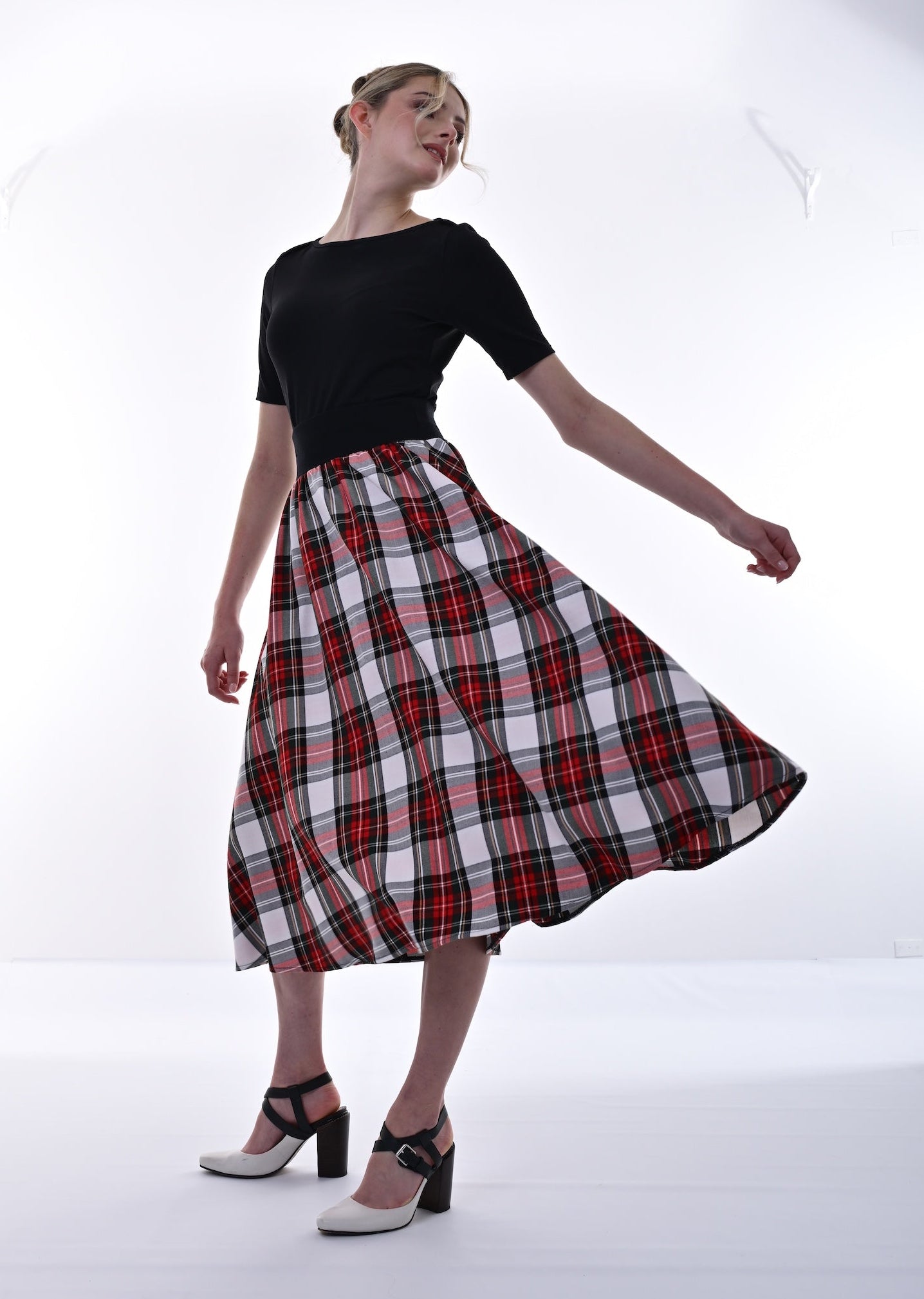 Woman wearing a black top and red plaid skirt on a white background