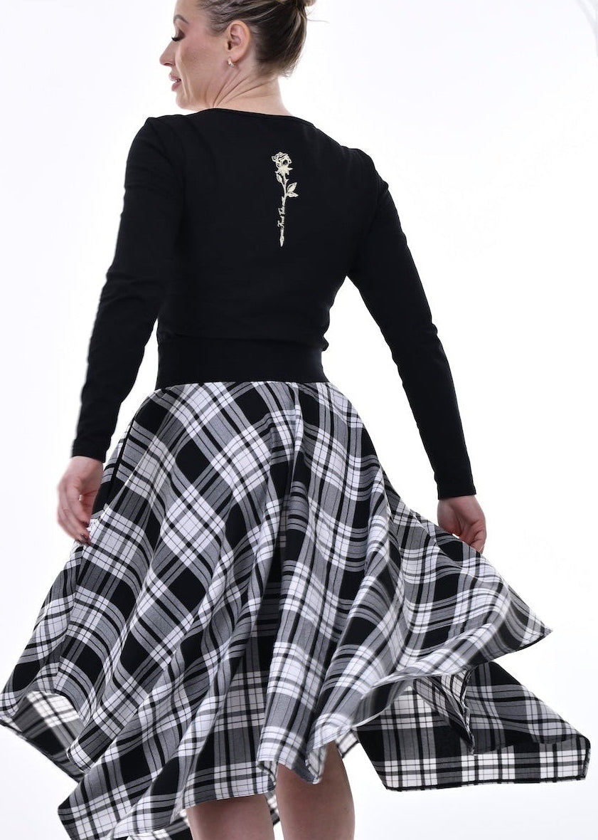 Woman wearing a black top and plaid skirt in a white room