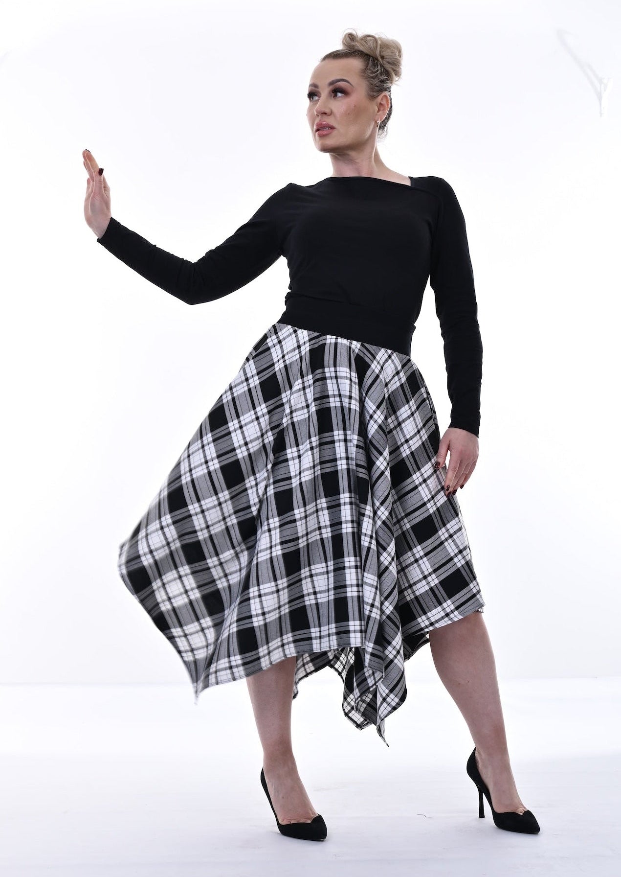 Woman wearing a black top and plaid skirt on a white background