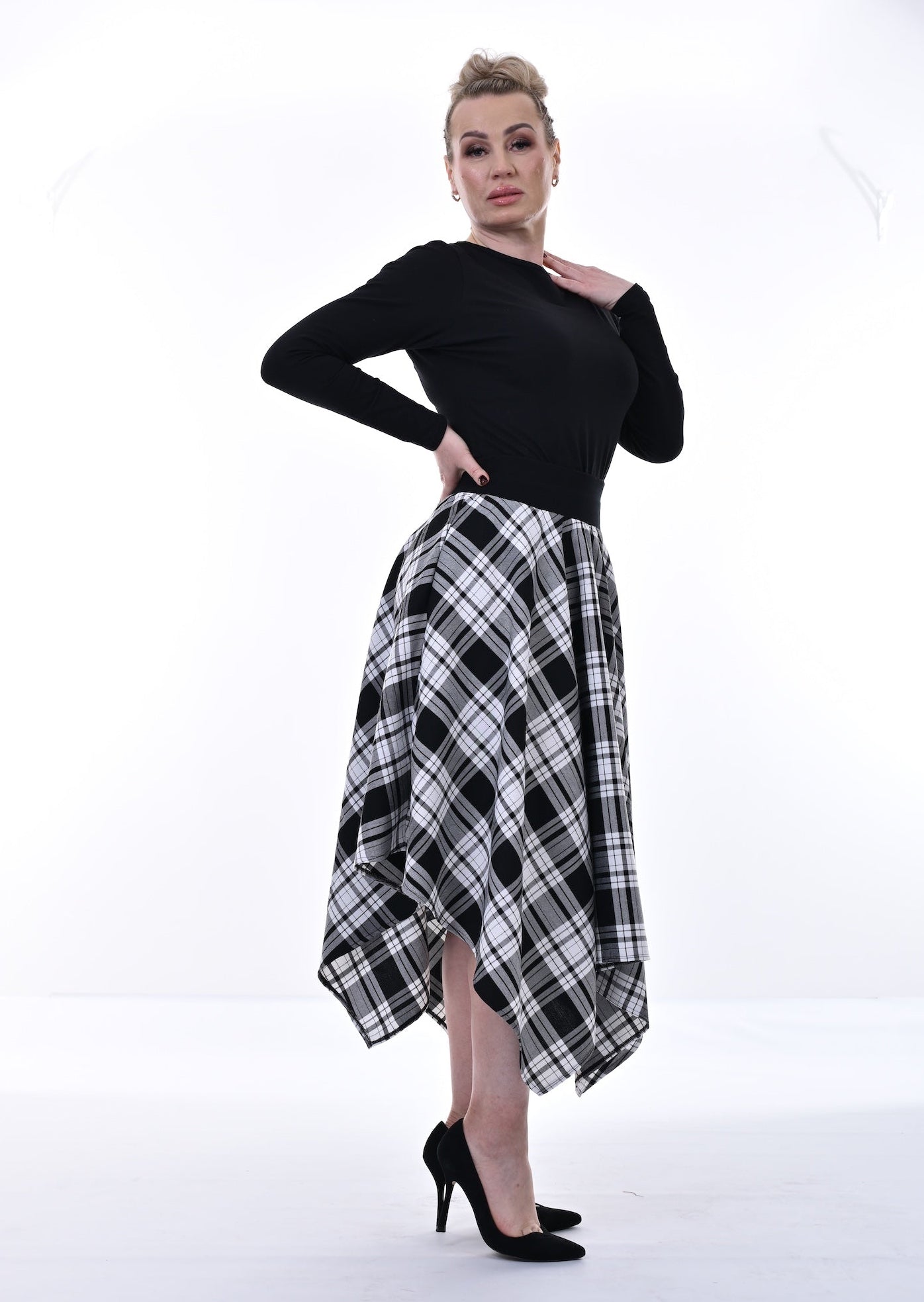 Woman wearing a black top and plaid skirt in a studio setting
