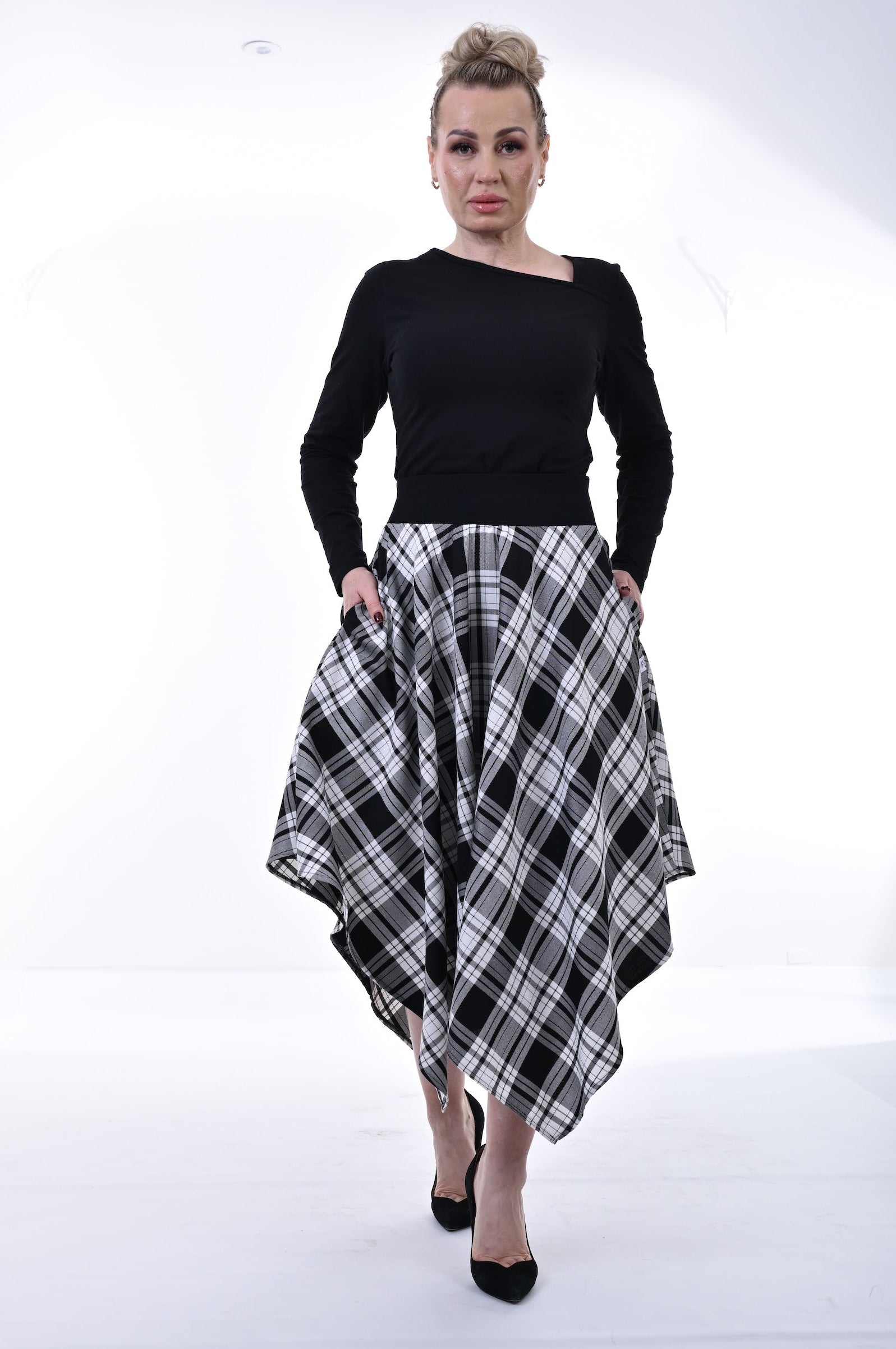 Woman wearing a black top and plaid skirt on a white background