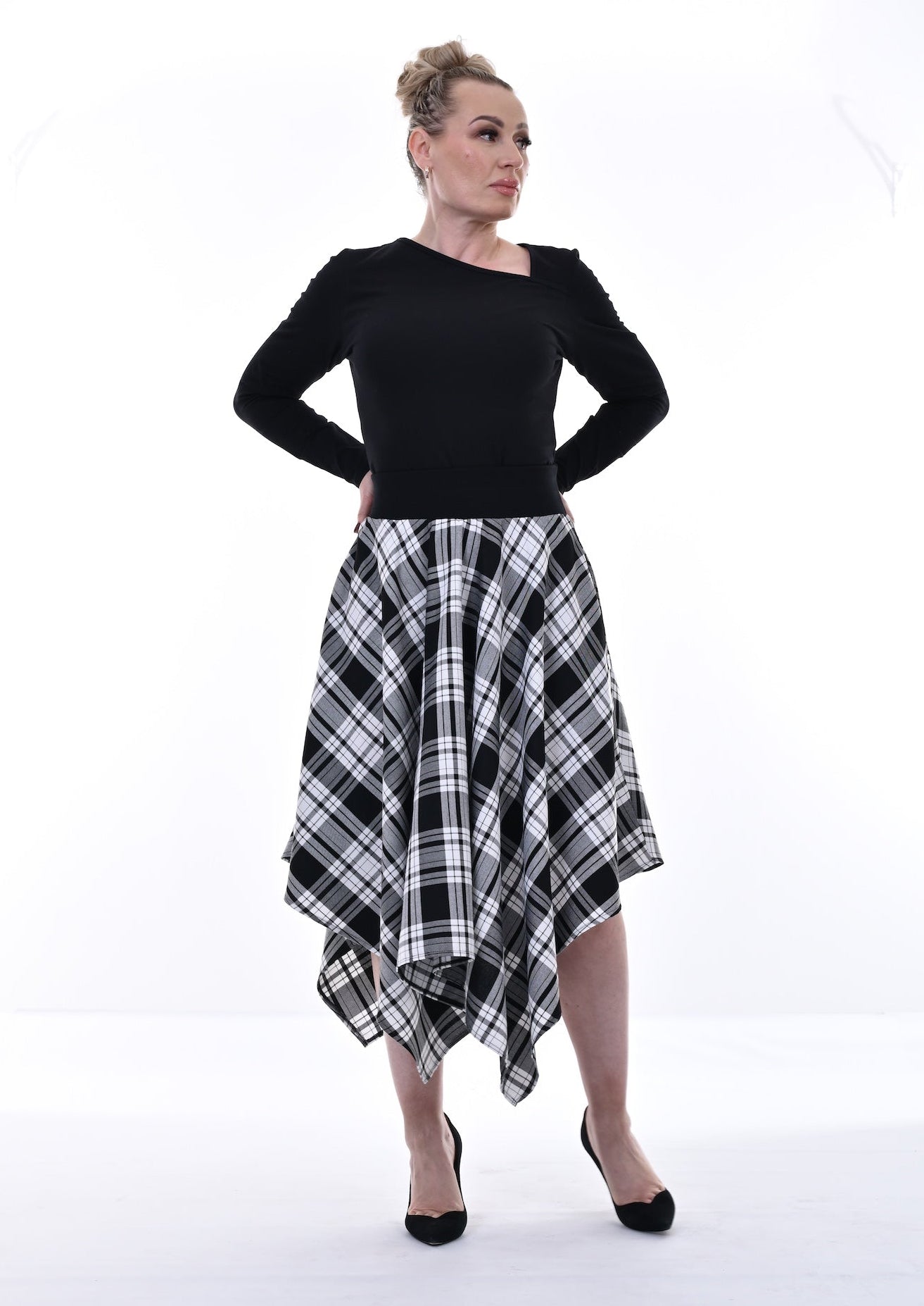 Woman wearing a black top and plaid skirt on a white background