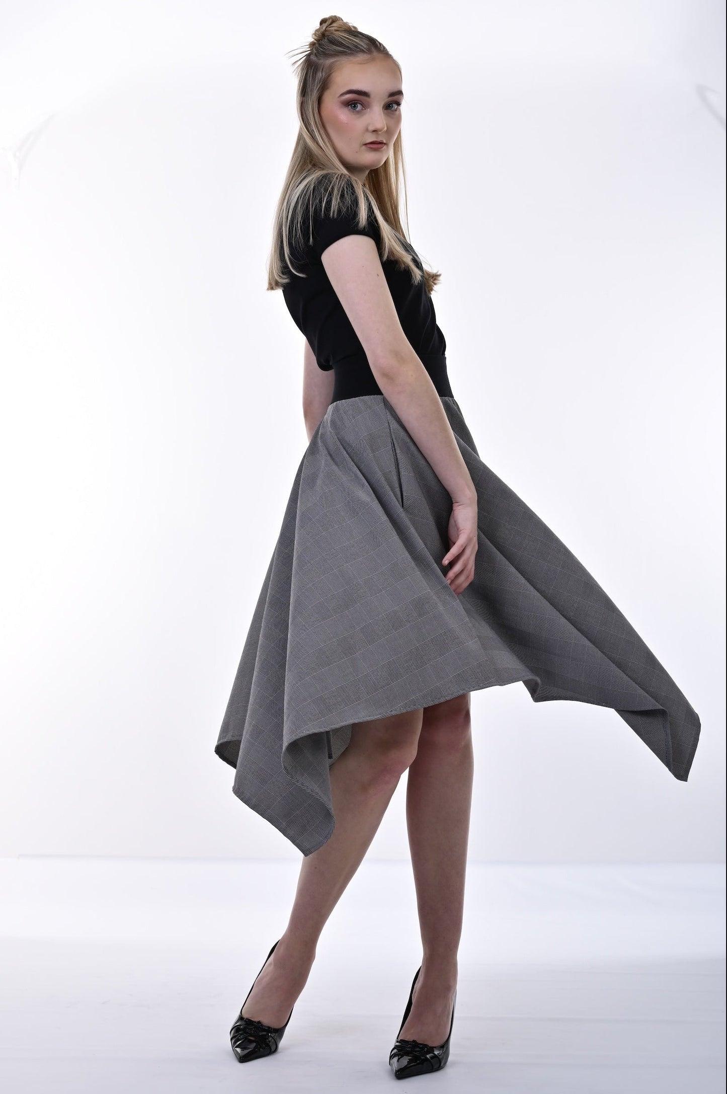 Woman wearing a black top and gray skirt on a white background