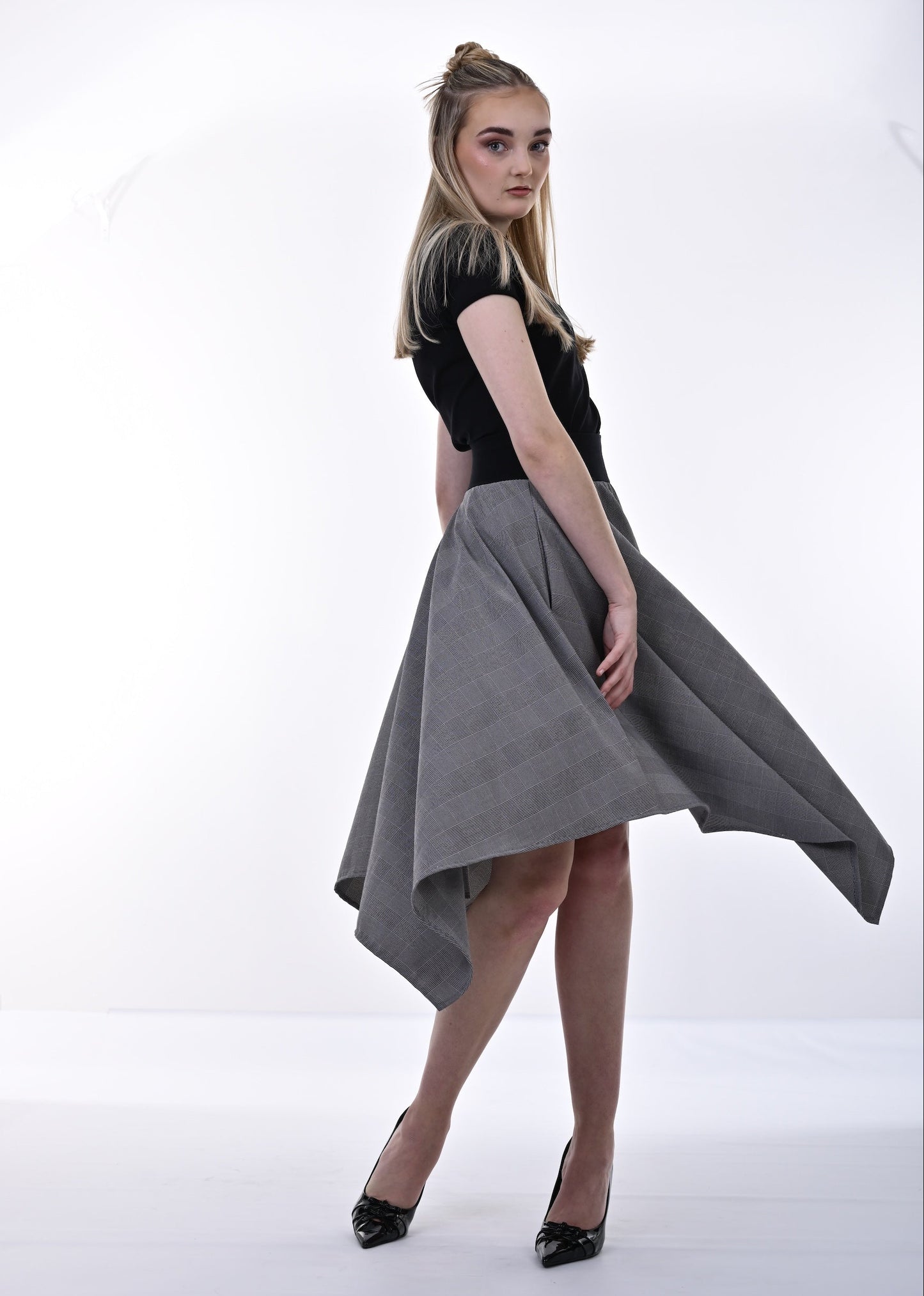 Woman wearing a black top and gray skirt on a white background