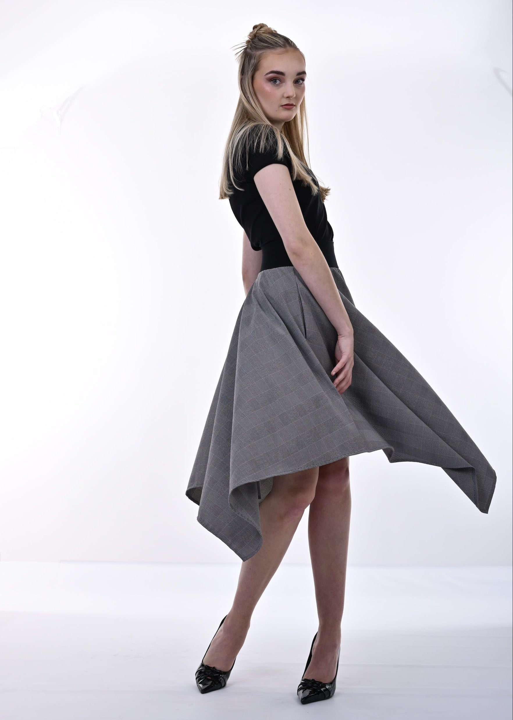 Woman wearing a black top and gray skirt on a white background