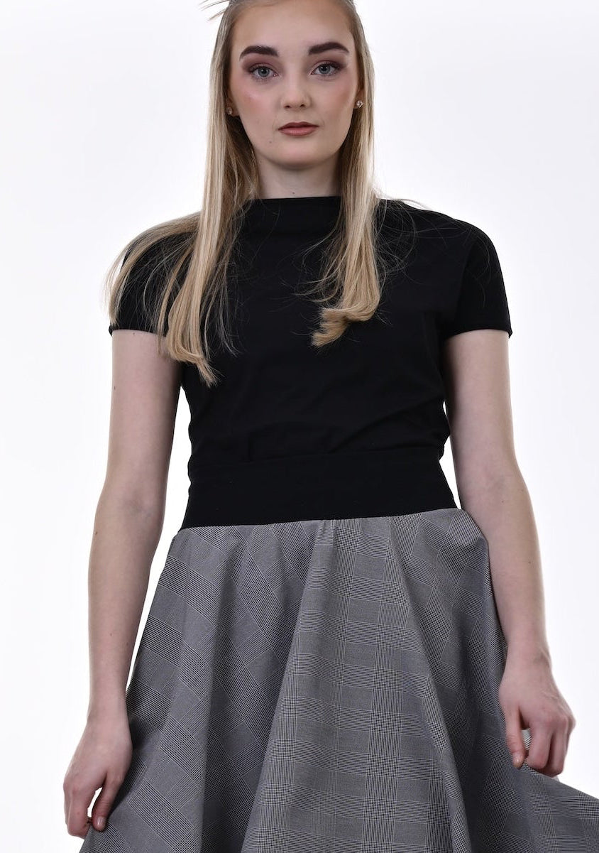 Woman wearing a black top and gray skirt on a white background