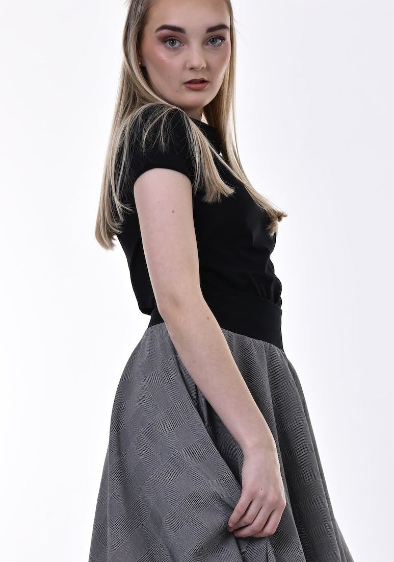 Woman wearing a black top and gray skirt on a white background