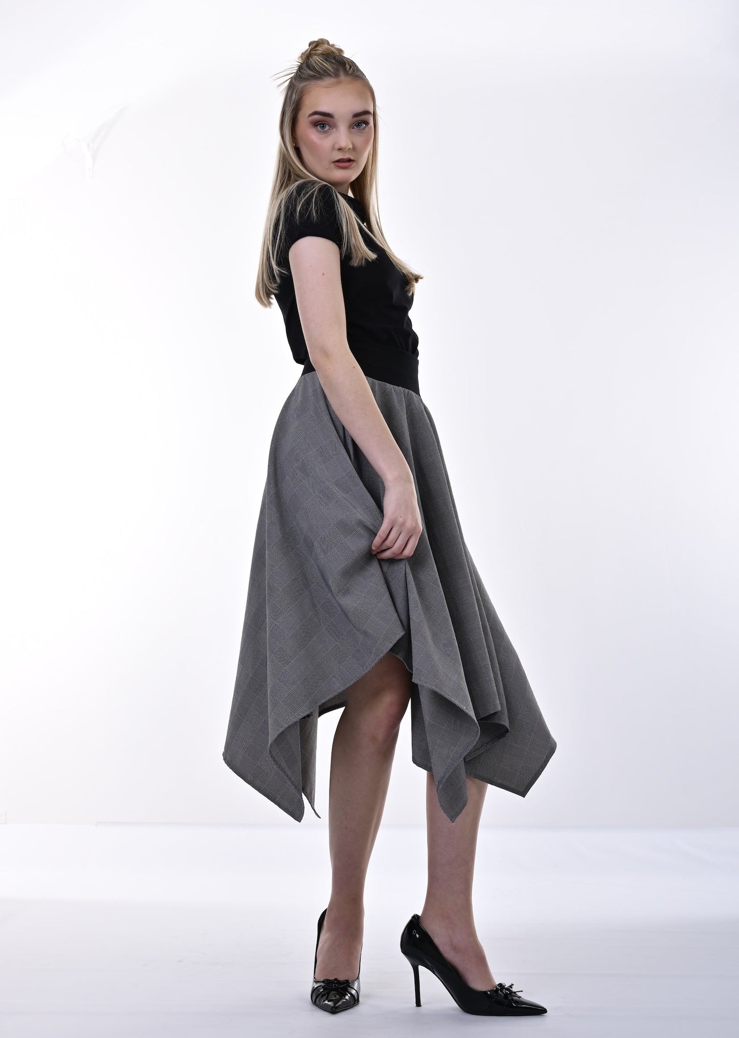 Woman wearing a black top and gray skirt on a white background