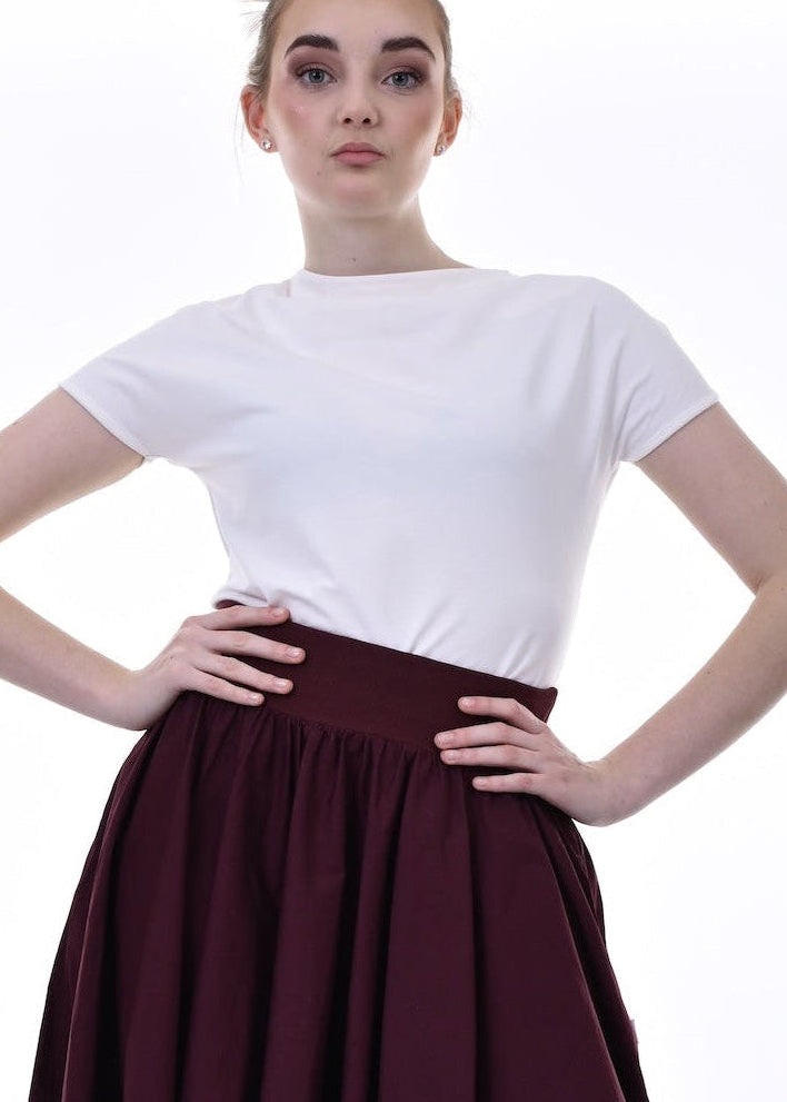Person wearing a white top and burgundy skirt on a white background