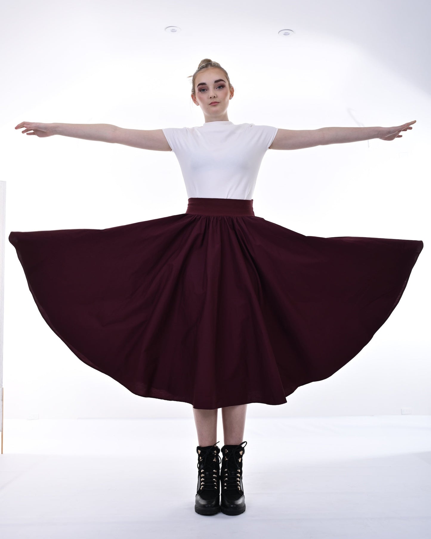 Person wearing a white top and burgundy skirt on a white background