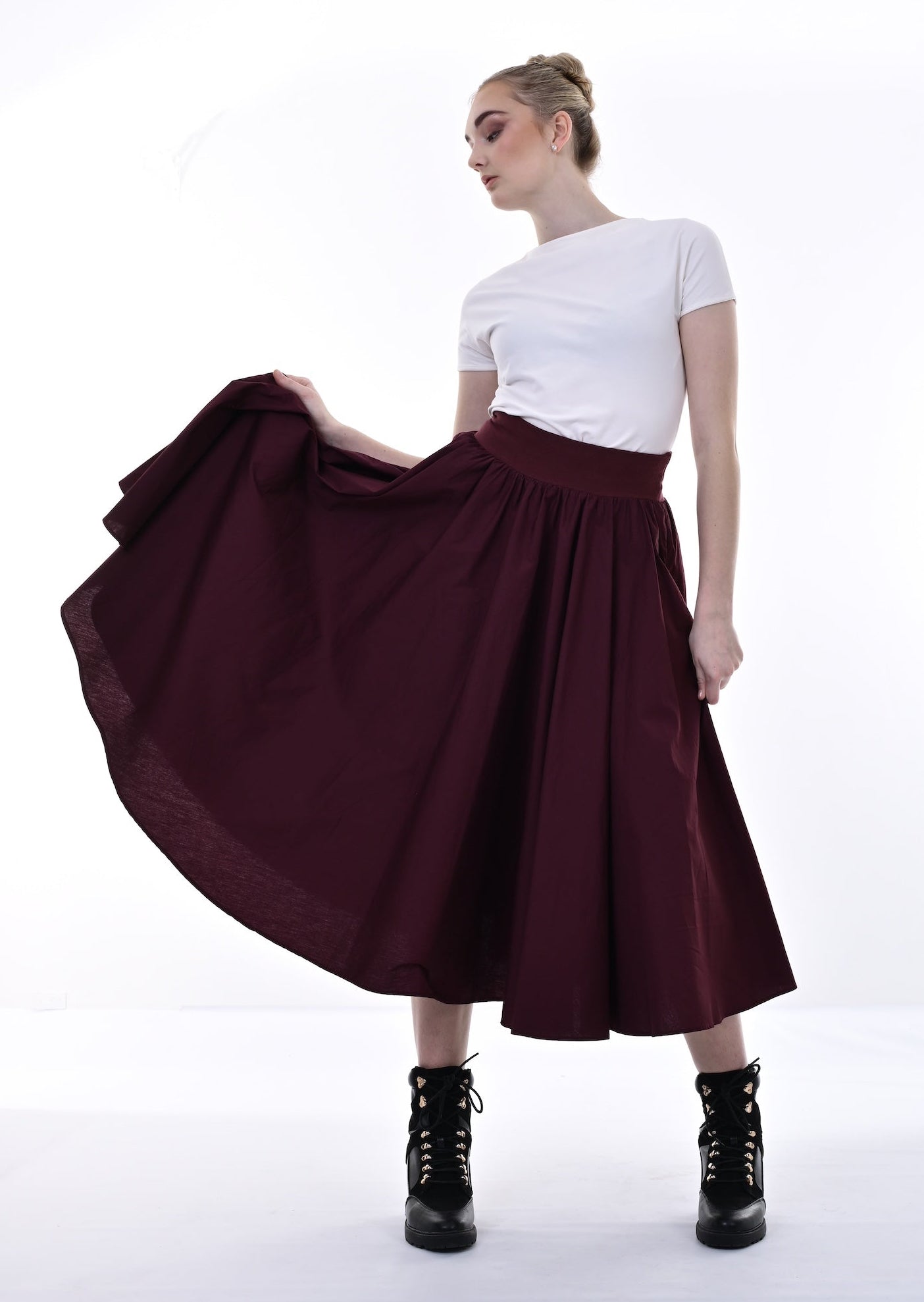 Woman wearing a white top and burgundy skirt on a white background