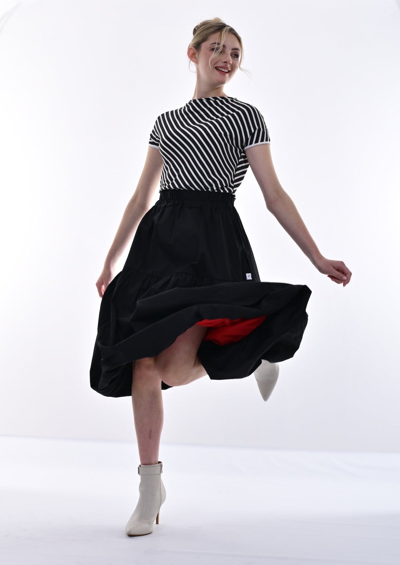 Woman wearing a black and white striped shirt with a black skirt in a studio setting
