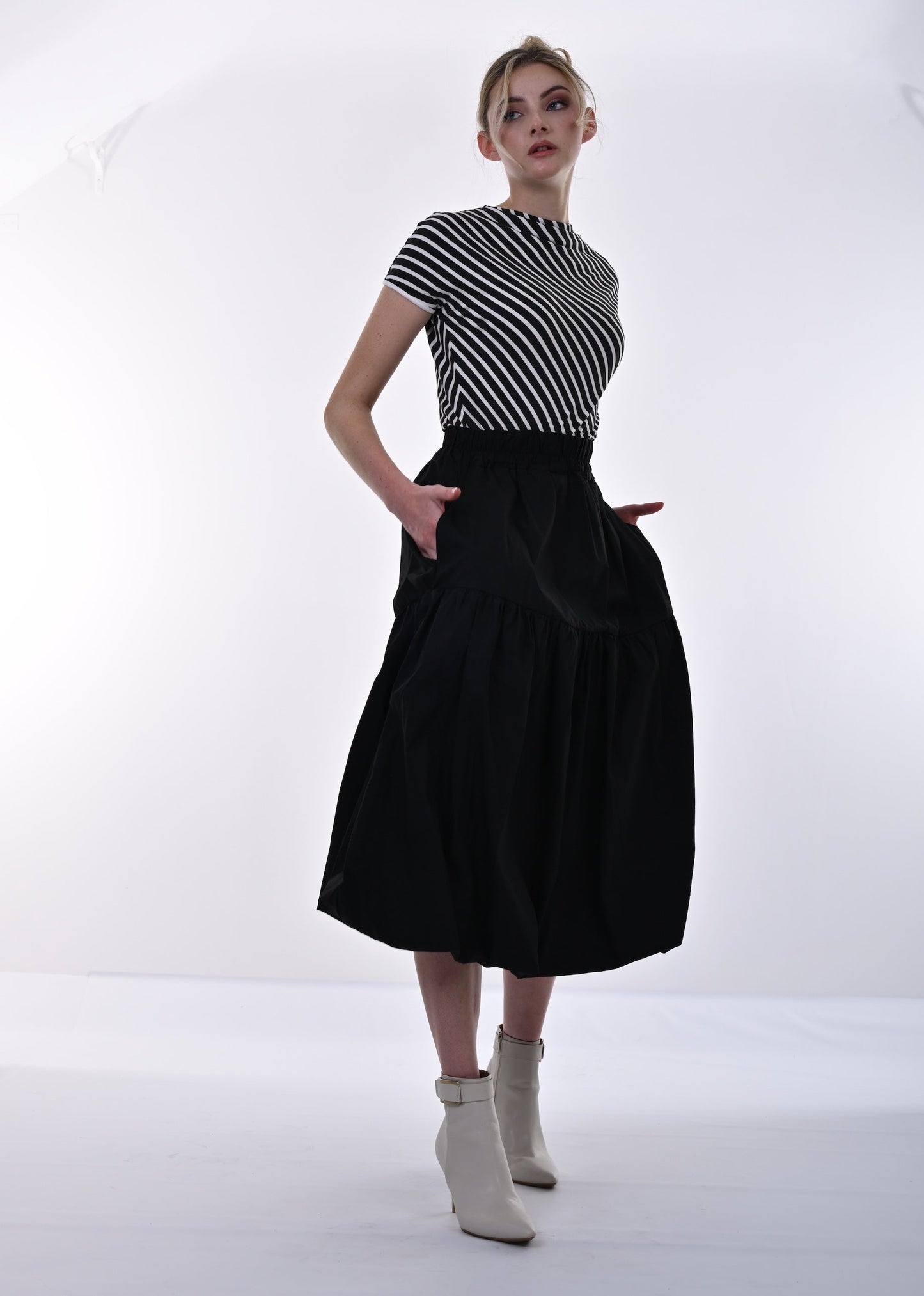 Person wearing a black and white striped shirt with a black skirt on a white background