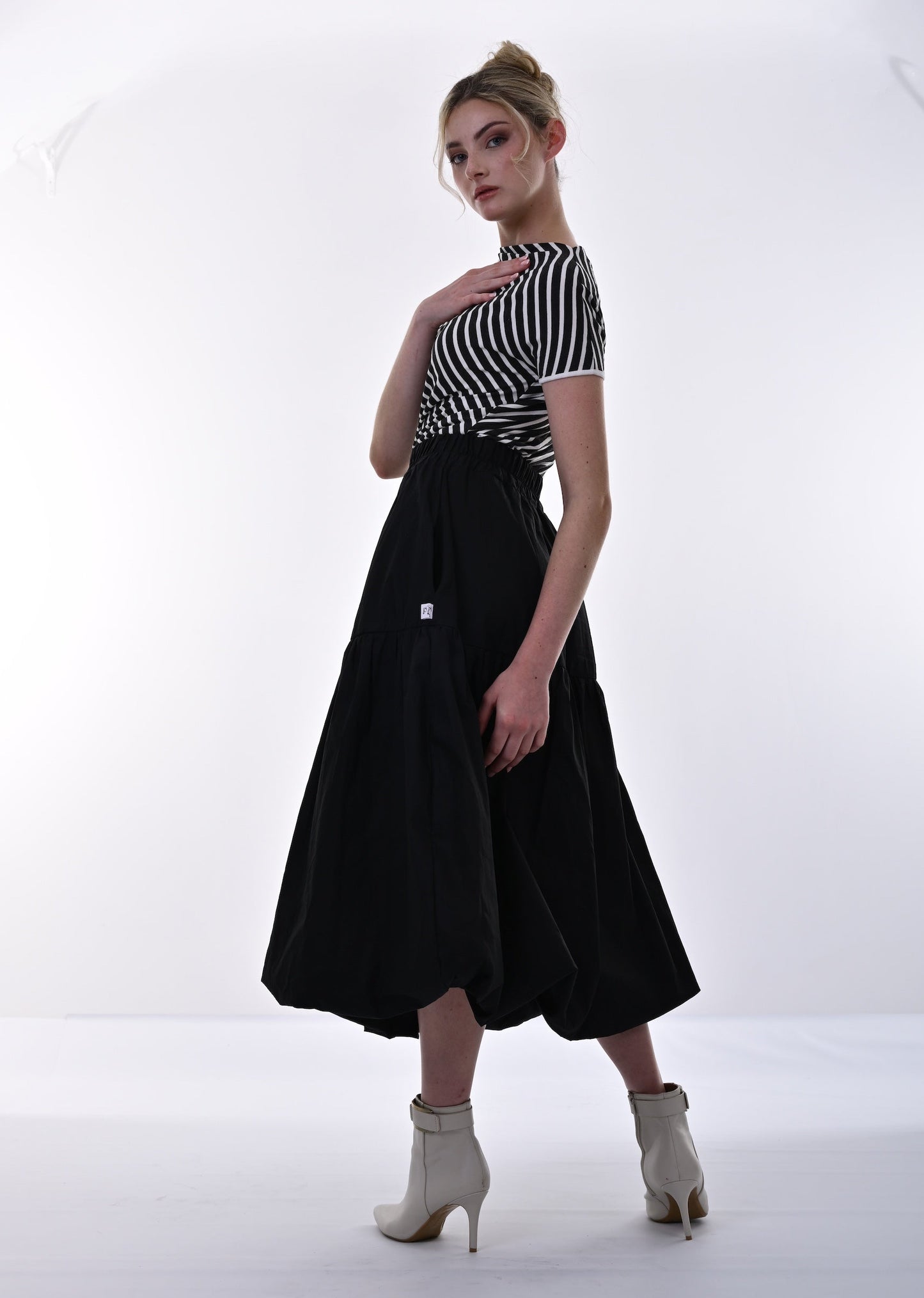 Woman wearing a black and white striped top with a black skirt on a white background