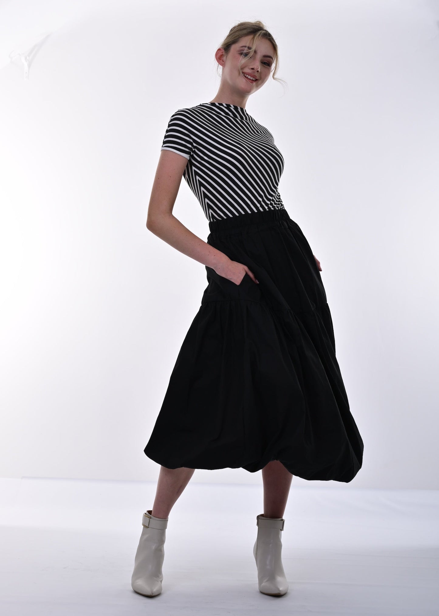 Person wearing a black and white striped shirt and black skirt on a white background
