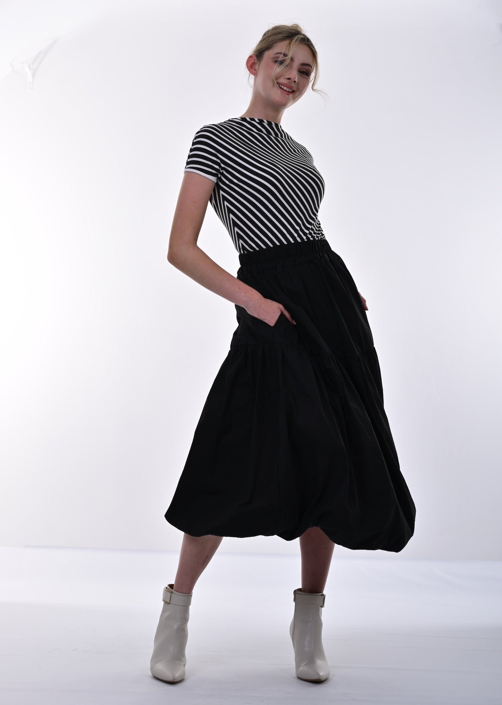 Person wearing a black and white striped shirt and black skirt on a white background