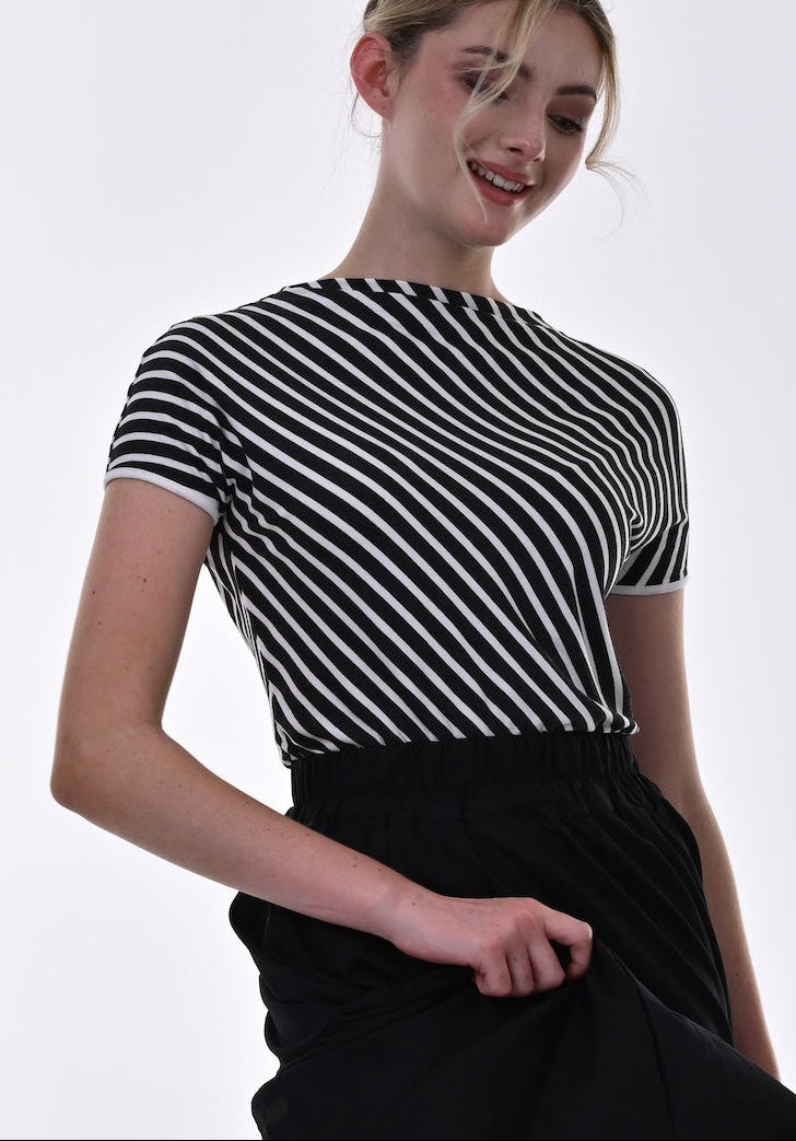 Woman wearing a black and white striped top with a black skirt and red lining, standing against a white background.