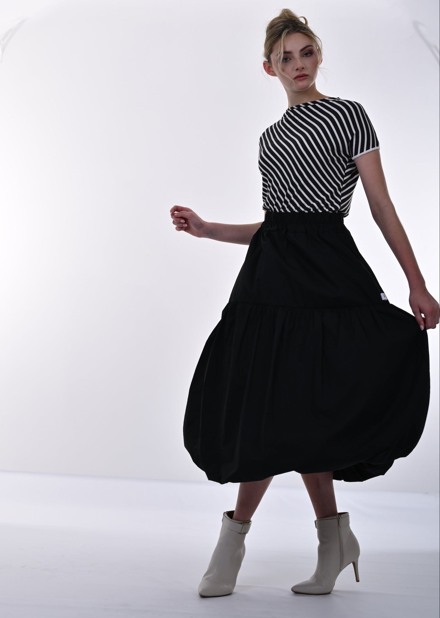 Woman wearing a black and white striped top and black skirt on a white background