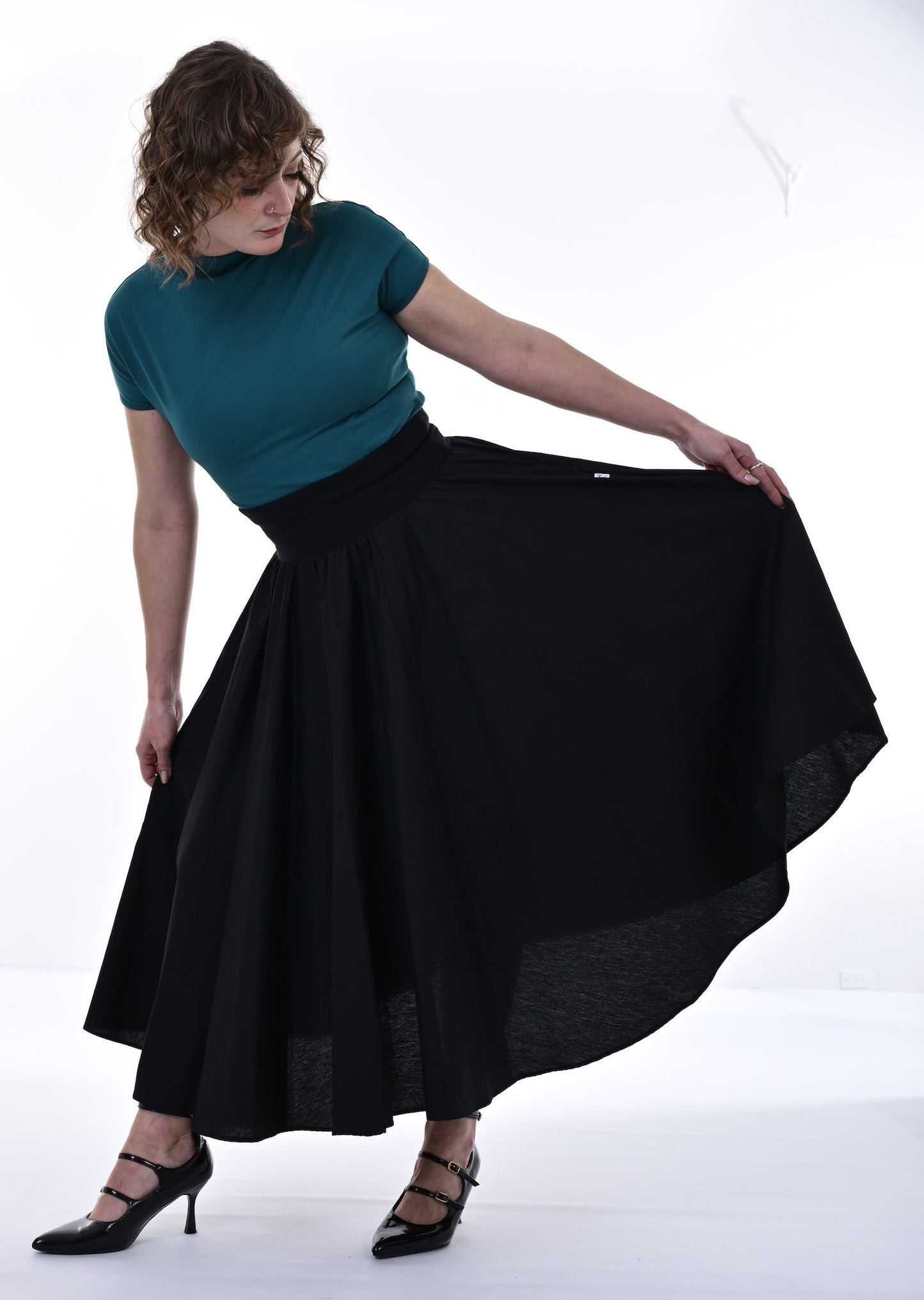 Woman wearing a teal top and black skirt on a white background