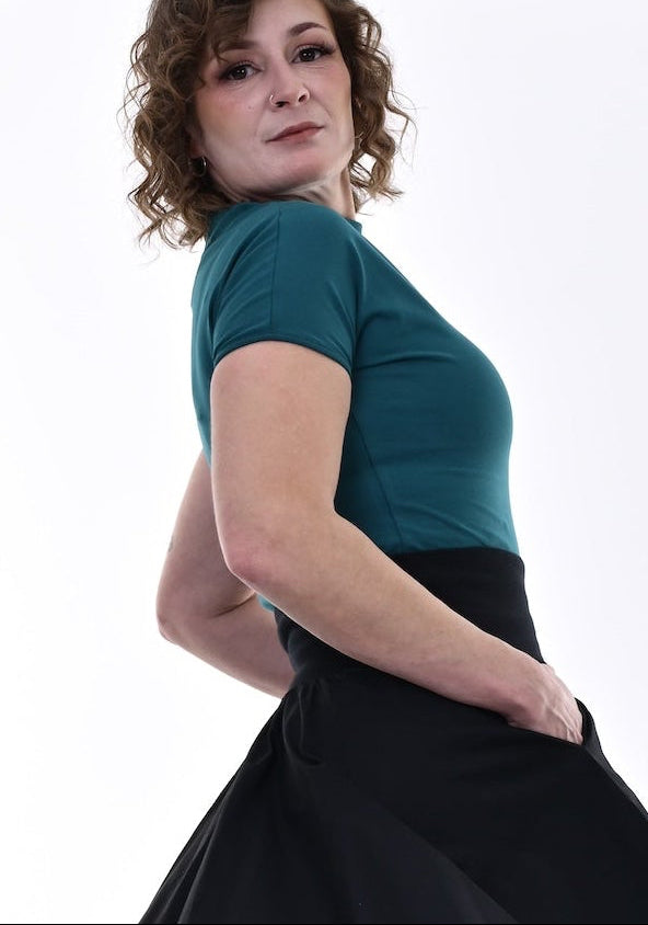 Woman wearing a teal top and black skirt on a white background