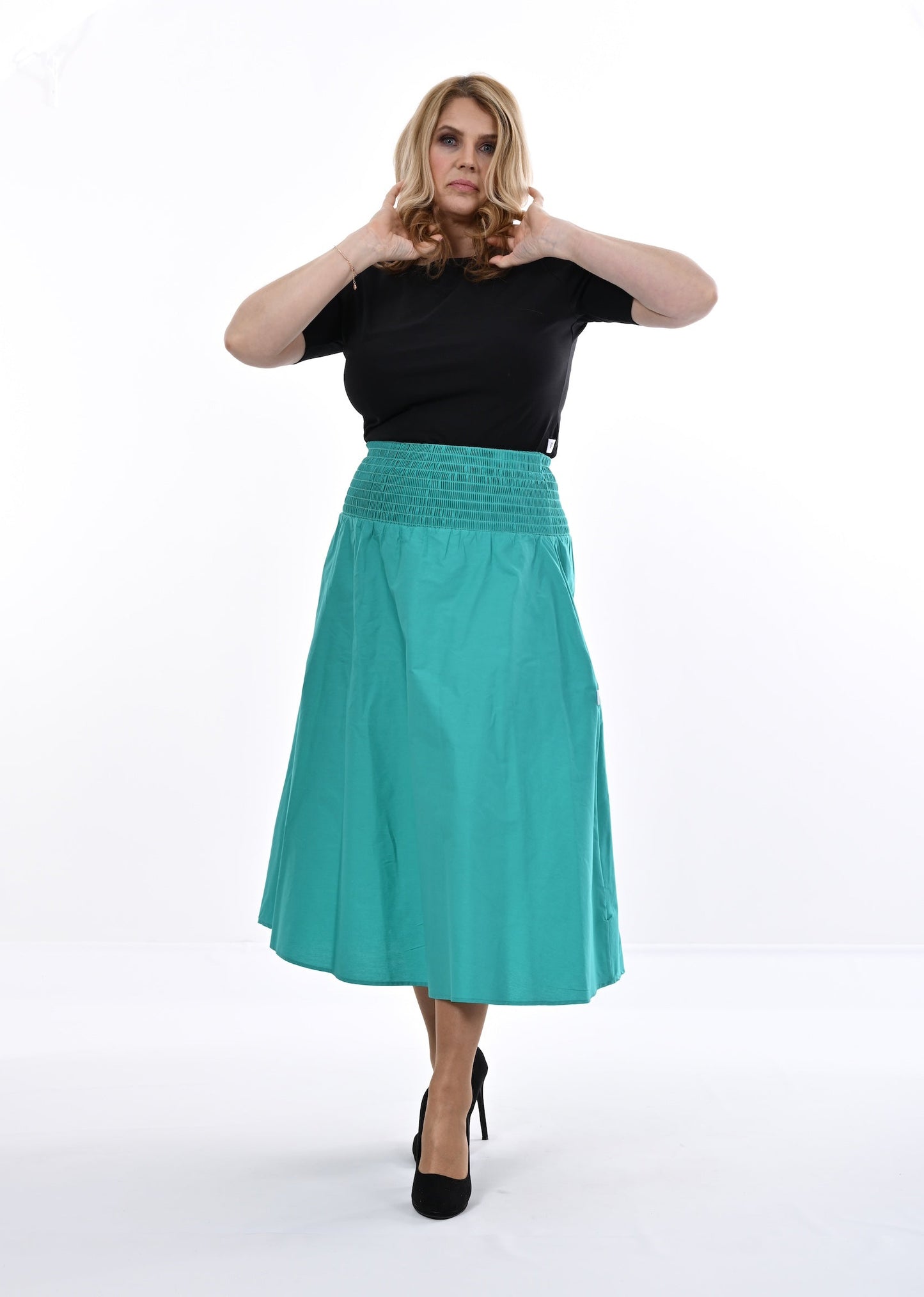 Woman wearing a black top and  an Aqua skirt on a white background