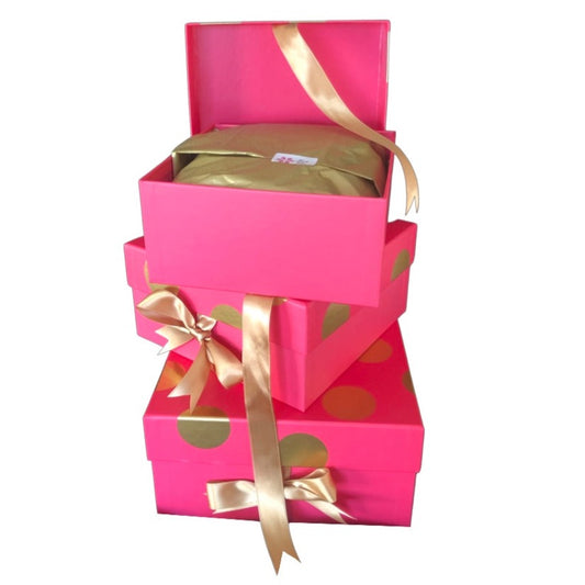 This is a stack of 3 pink boxes with gold spots and gold ribbons set against a white background.