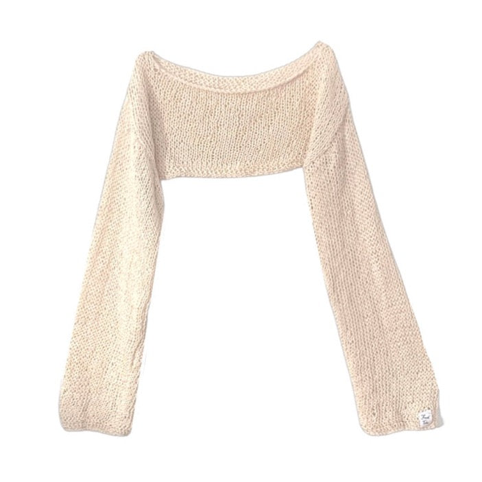 A hand knitted super cropped jumper in vanilla against a white background. The sleeves are long and slightly wider at the cuff. It has a dropped shoulder and sits above the bust.