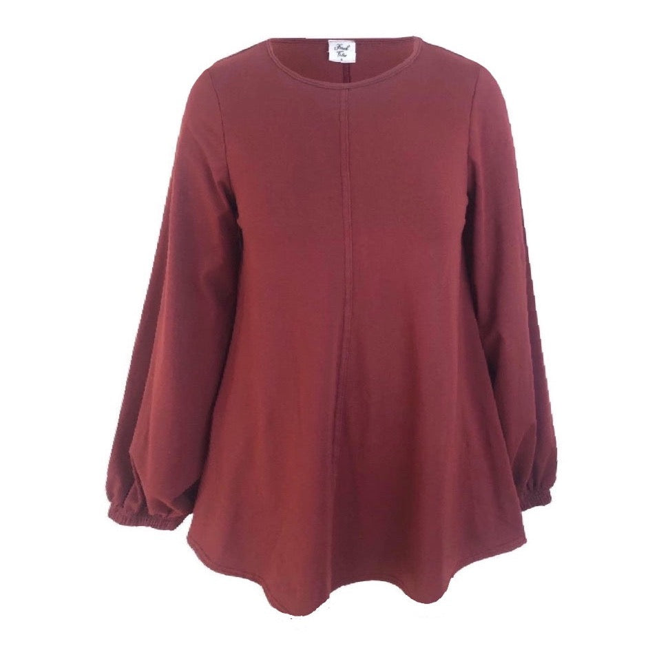 This hip length flared top in wine is shown against a white background. It has long loose sleeves that gather in to a cuff at the wrist. There is a feature centre front seam and it has a round neck.